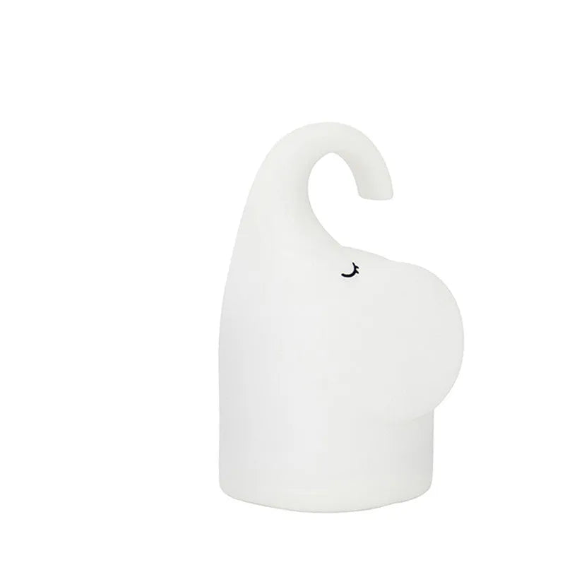 White silicone elephant-shaped night light with a warm glow, placed on a wooden bedside table.