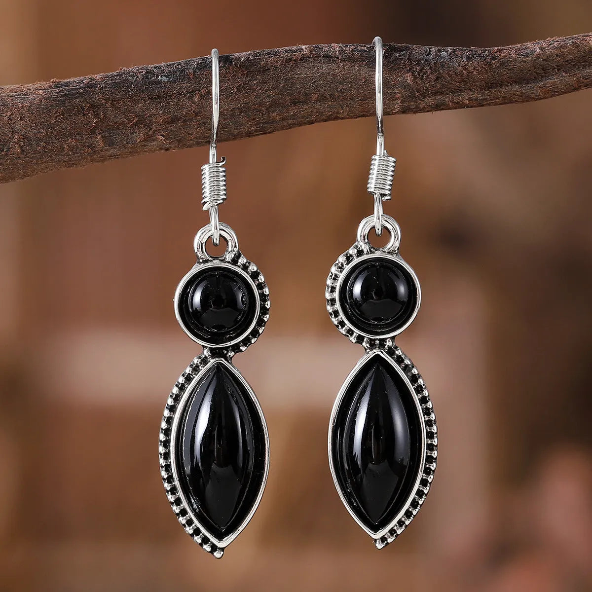 A pair of vintage geometric drop earrings with a round gemstone, in black and purple electroplated zinc alloy.