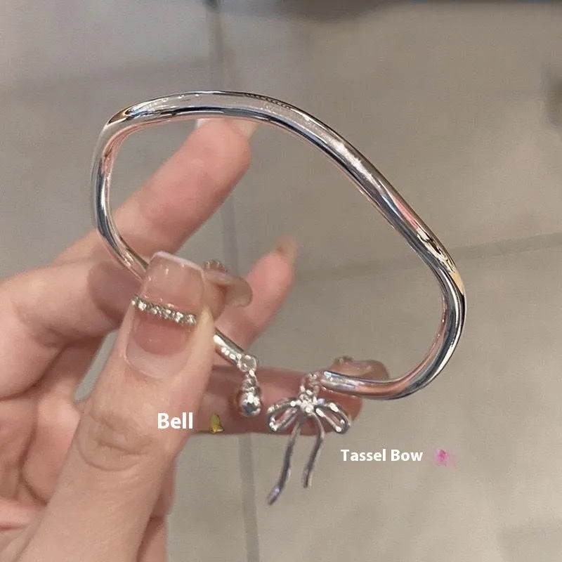 Silver-coloured adjustable bracelet with a bow charm on a wrist.