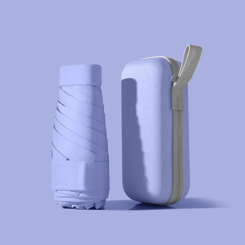 Ultra-light six-fold flat sun umbrella in sky blue with a rubber handle, shown with its capsule storage box.
