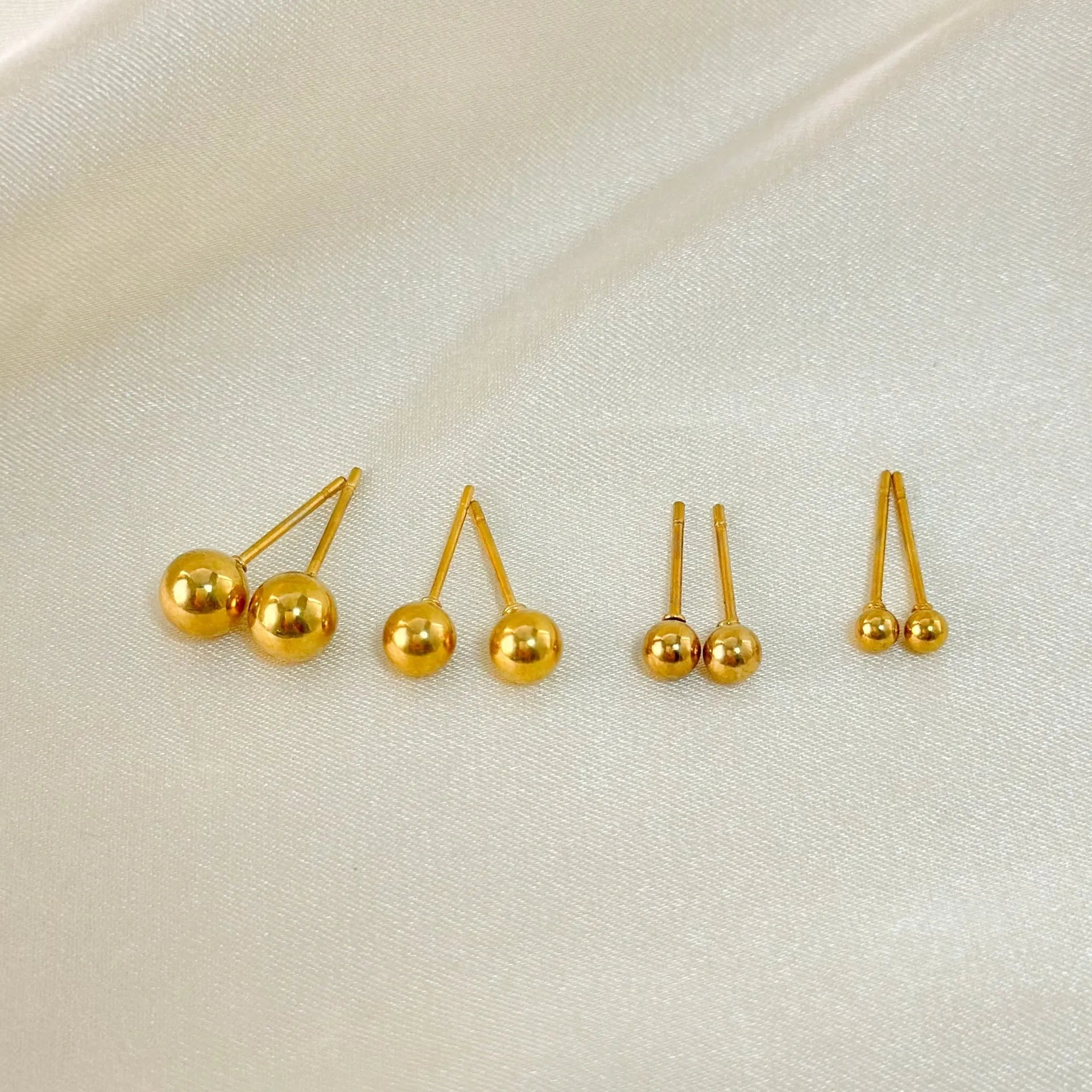 Titanium steel 18K gold electroplated ball stud earrings in round geometric design on white background.