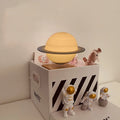 Maglev floating moon planet night light with three astronaut figurines on a dark surface.