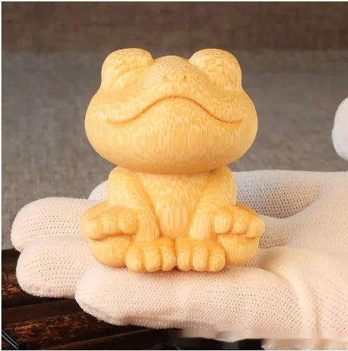 Small smiling frog ornament carved from solid bamboo on a plain background.