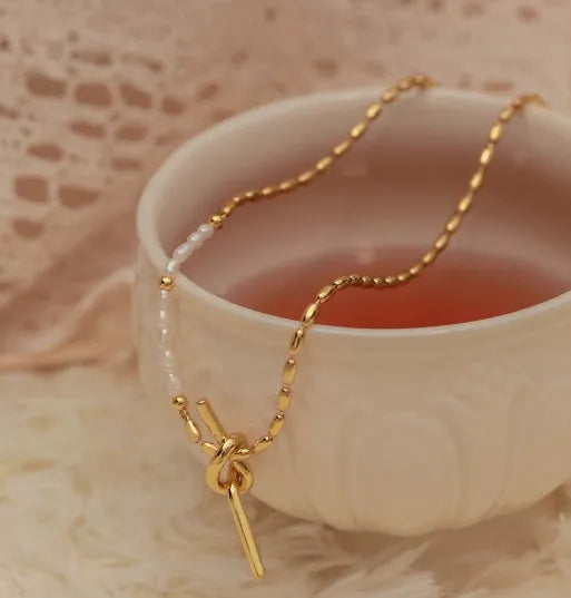 Gold electroplated natural real pearl necklace with copper geometric pendant and ring-line design on white background