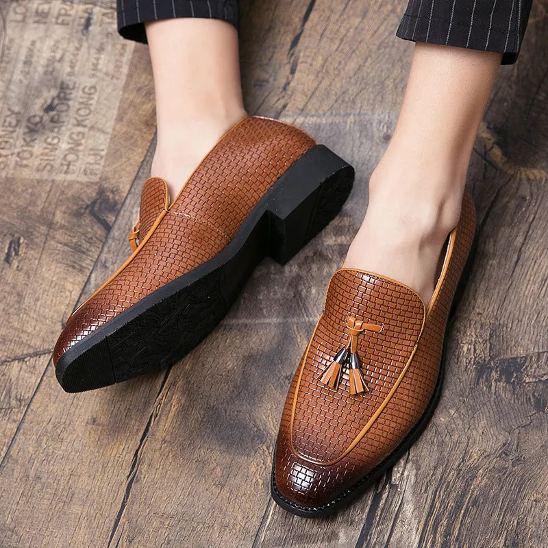 Men's black slip-on leather loafers with a pointed toe and tassel detail on a white background.