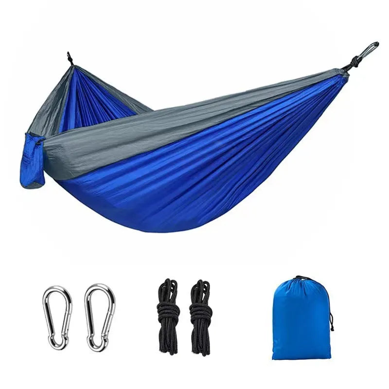 Blue parachute nylon outdoor hammock hung between two trees in a garden setting