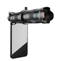 APEXEL 28 times telephoto lens black aluminium alloy with lens cap on table beside smartphone