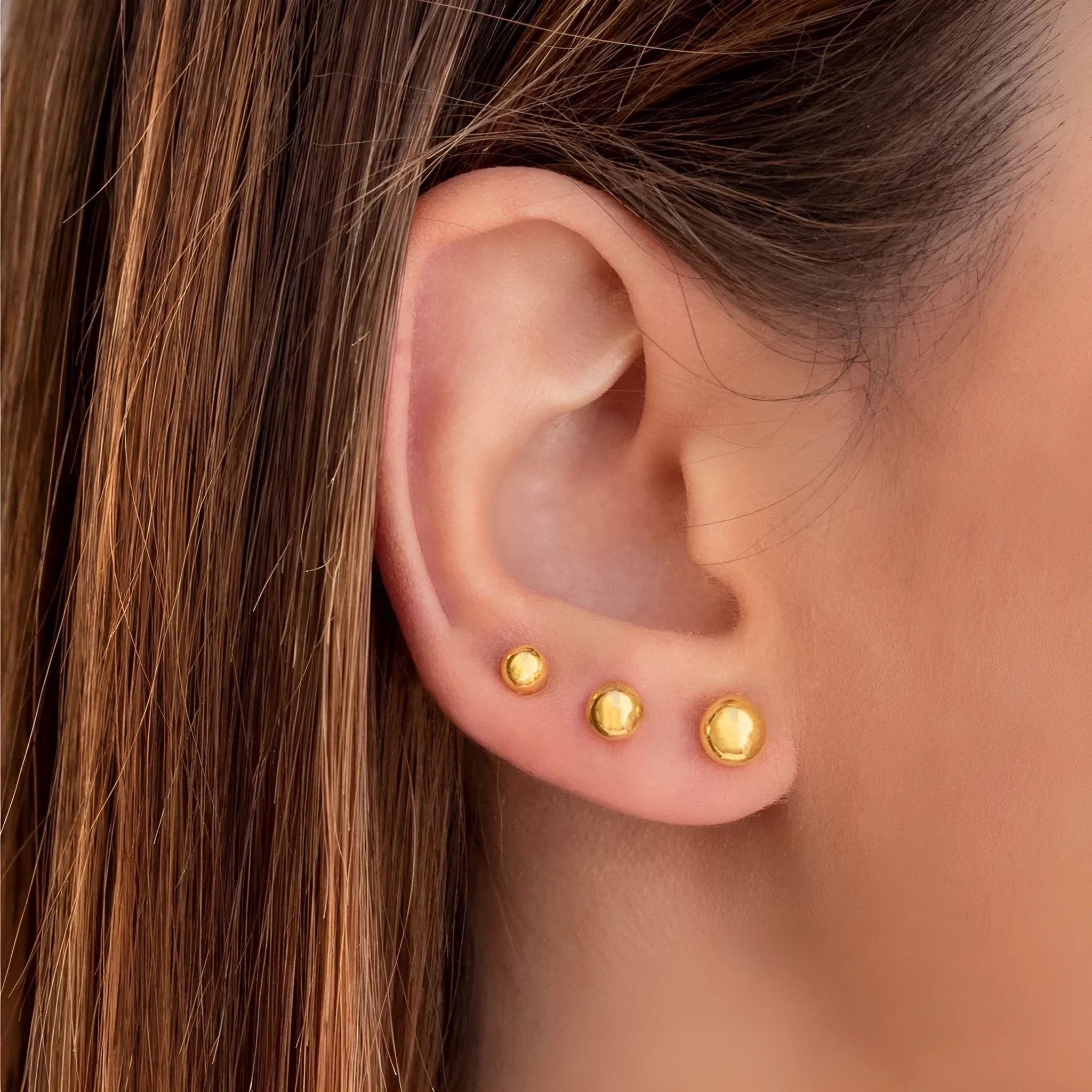 Titanium steel 18K gold electroplated ball stud earrings in round geometric design on white background.