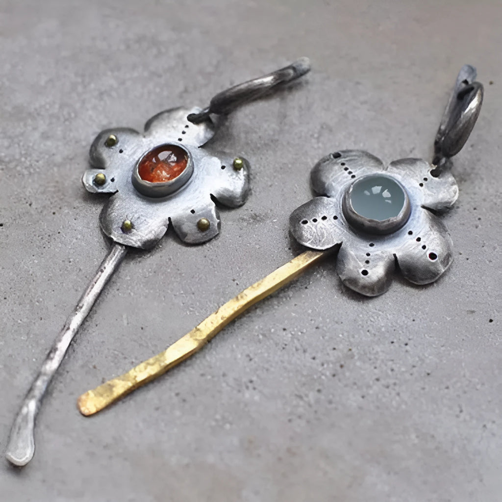 A pair of long retro-style earrings with a geometric floral shape in an asymmetric two-tone colour finish.