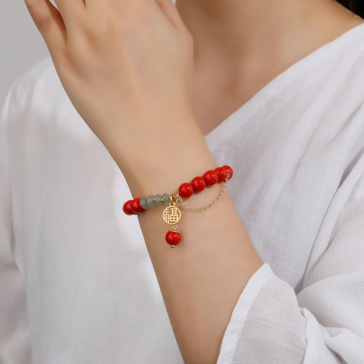 Retro women's bracelet with red sand cinnabar fu character pendant, jade spacer beads, and tassel detailing