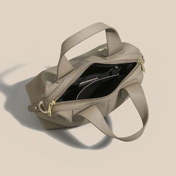 Women's leather cross-body bag in horizontal square shape with visible sewing thread detailing and interior compartments