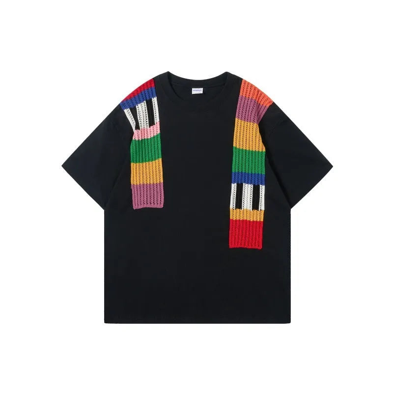 Man wearing a loose black cotton pullover with a white and grey patchwork letter pattern on the front.