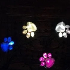 Black bear paw print shaped solar garden lights installed along a garden path.