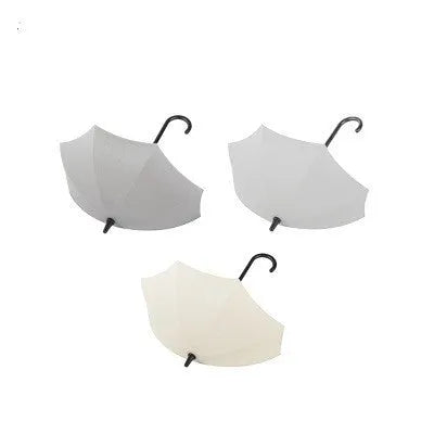 3 plastic umbrella-shaped sticky hooks in Nordic pink blue green, on a white door, holding keys