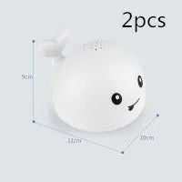 Whale-shaped electric bath toy spraying water with flashing lights, floating in baby bathtub