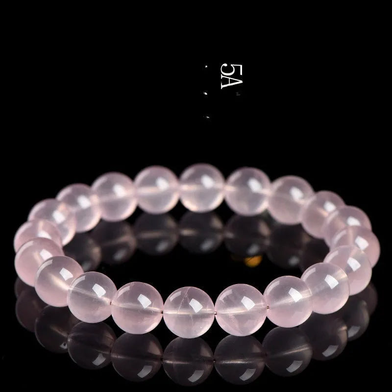 Natural starlight crystal round beads women's bracelet in pink on a wrist, showing polished single circle beads.