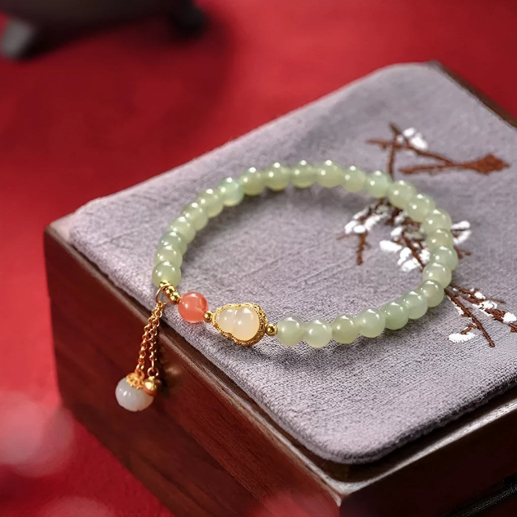 Natural jade bracelet with a gold-plated gourd charm and fu character charm.