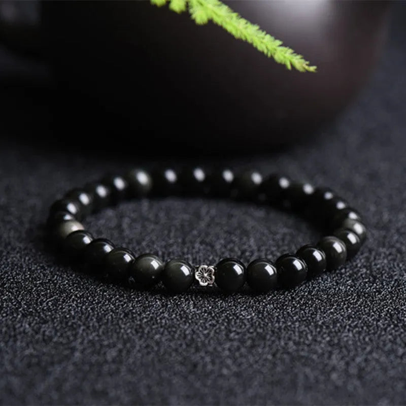Natural obsidian bracelet with S925 sterling silver flower accessories on a wrist