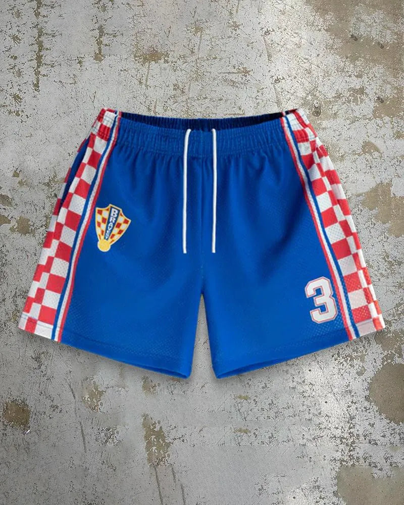 Man's loose blue digital print beach shorts with elastic waistband on a sandy background.