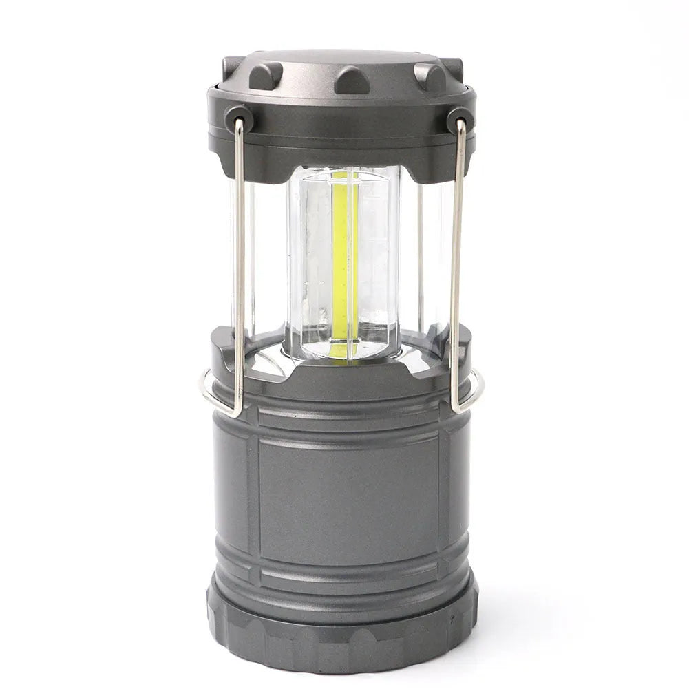COB LED camping lamp in black with telescopic body and hook, standing on a wooden surface