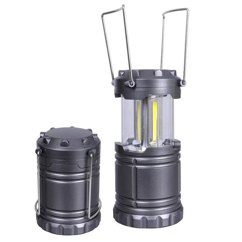 COB LED camping lamp in black with telescopic body and hook, standing on a wooden surface