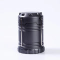 COB LED camping lamp in black with telescopic body and hook, standing on a wooden surface