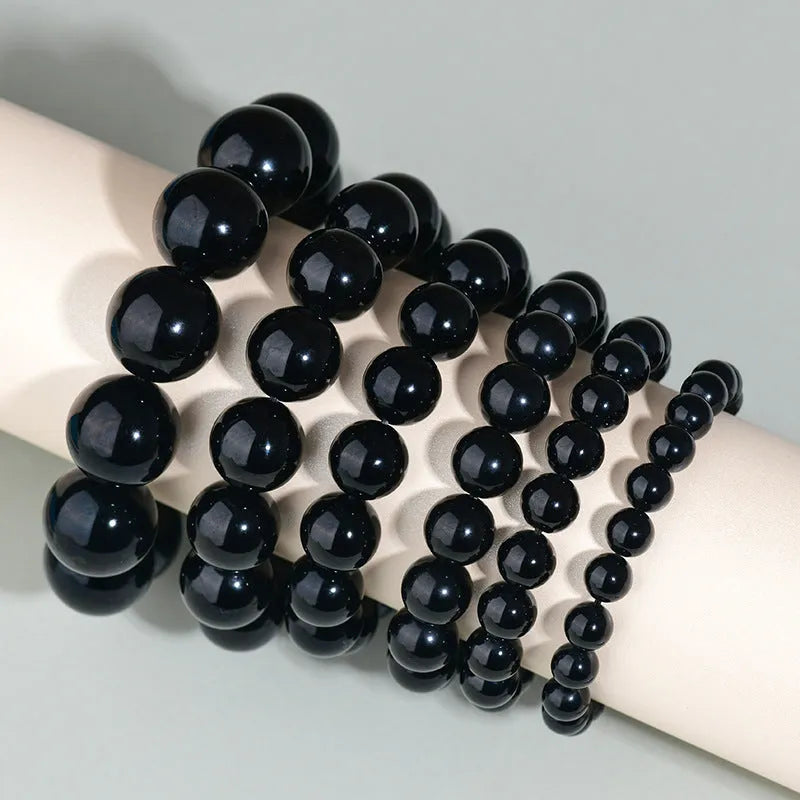 Hand-woven round obsidian crystal bracelet for couples on wrist, showing ethnic style and adjustable fit.
