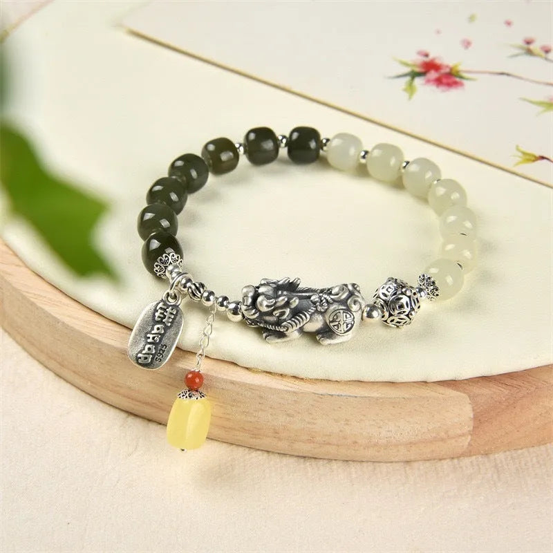 Close-up of a women's silver bracelet with Hetian jade beads and an 8x7mm retro coin charm.