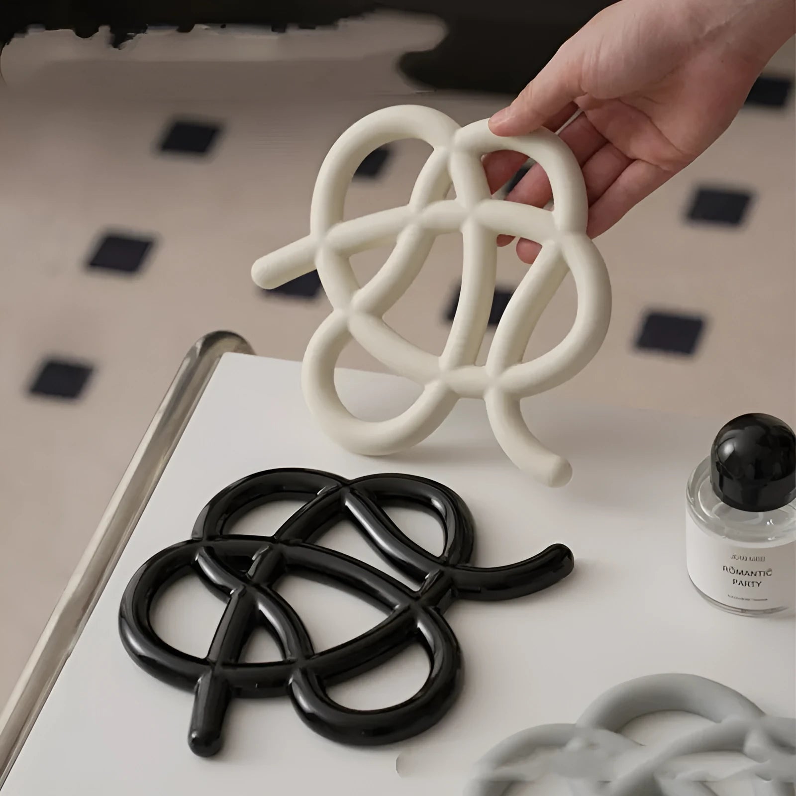 Ceramic heat proof mat in irregular shape on a table, shown in bright black colour.