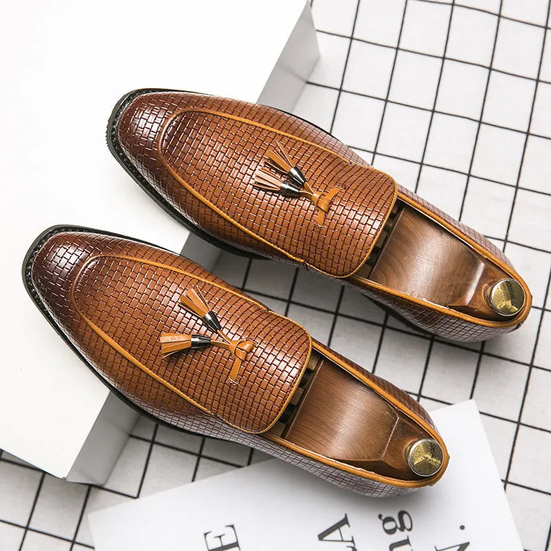 Men's black slip-on leather loafers with a pointed toe and tassel detail on a white background.