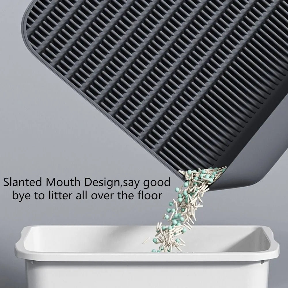 Large black cat litter pedal with slanted mouth and textured non-slip mat next to litter tray