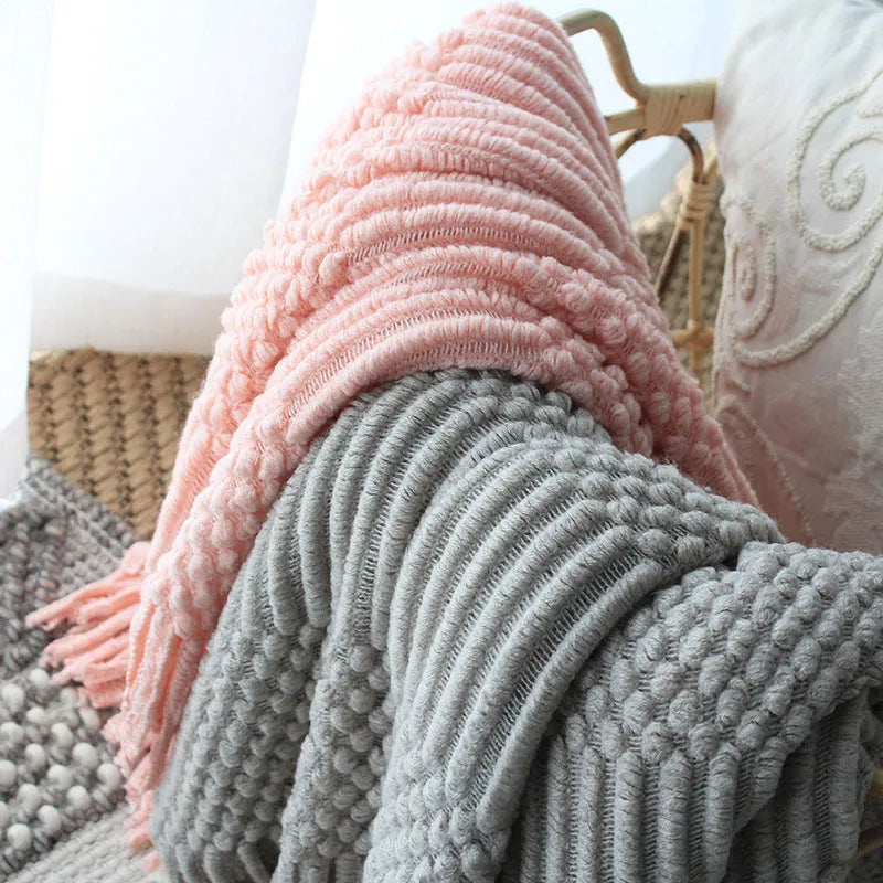 Nordic knitted bubble blanket in acrylic and polyester fibre, 127x170cm, shown as a plain sofa throw in light grey, light khaki, or pink.
