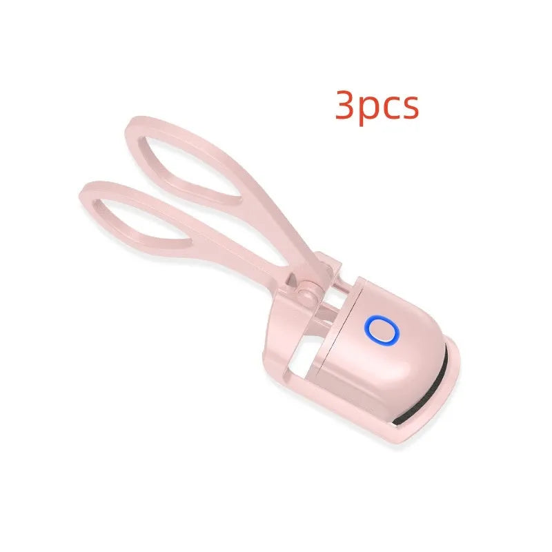 White USB rechargeable heated eyelash curler with dual temperature settings shown on a pink background.