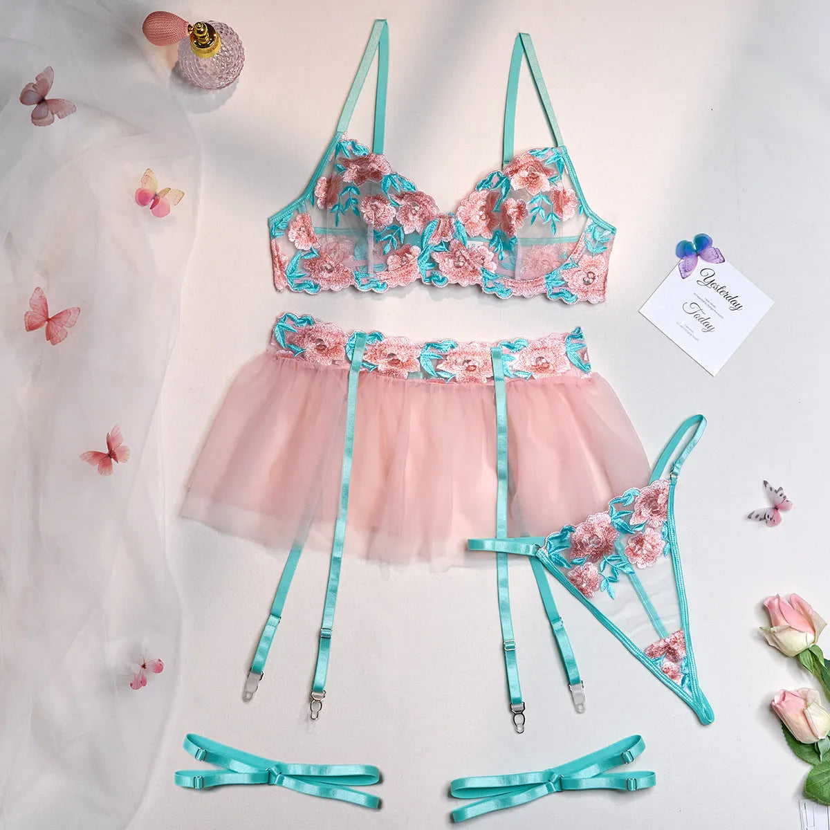 Pink embroidered women's bikini set with a matching mesh pettiskirt laid flat.