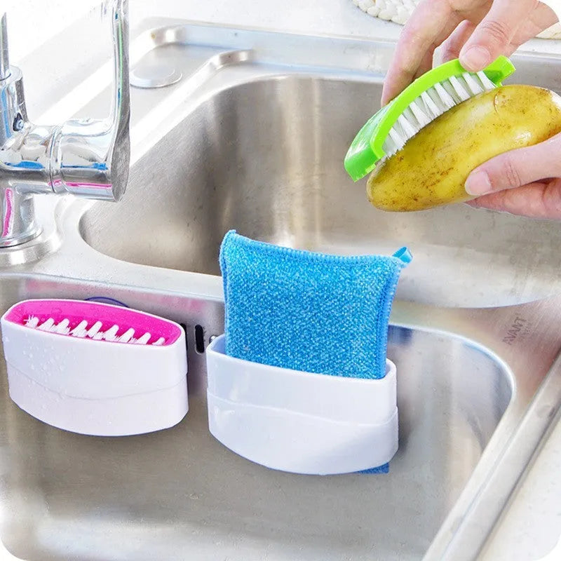 Blue kitchen cleaning brush with slots for utensils and a suction cup on a white wall.