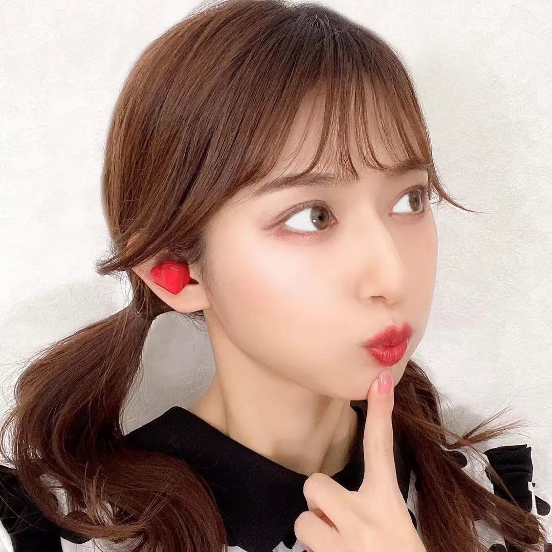 Red and pink heart-shaped wireless Bluetooth in-ear headphones with charging cable.