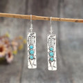 Silver geometric drop earrings with turquoise inlays and retro styling on white background