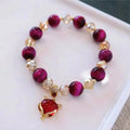Handmade Tigereye stone bracelet on wrist, showing single chain and rose red fox charm.