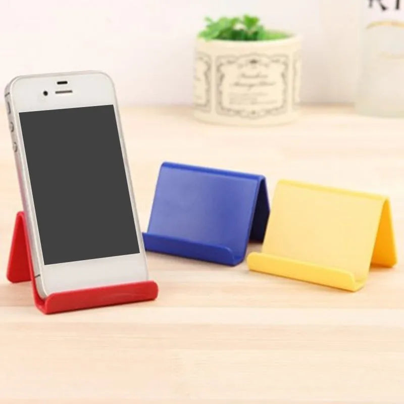 Small plastic mobile phone stand in blue, size 6x4.5cm, on a wooden desk