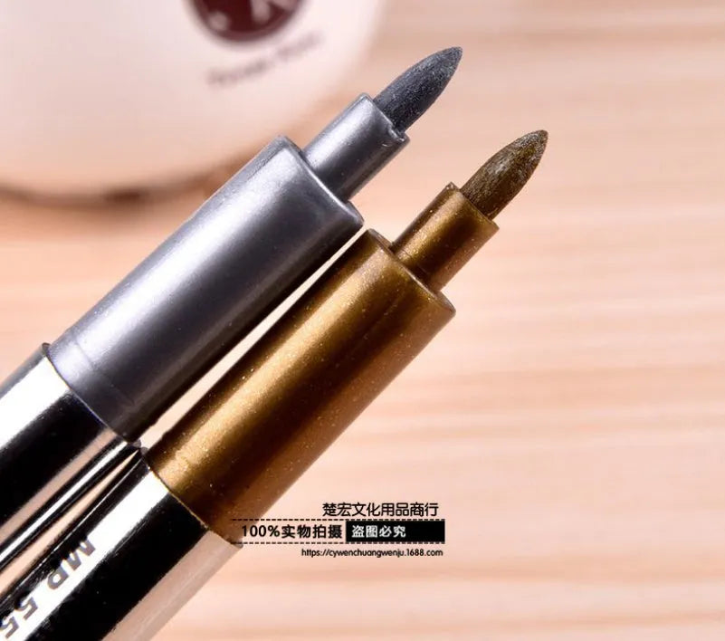 Gold and silver metallic marker pens on a white background