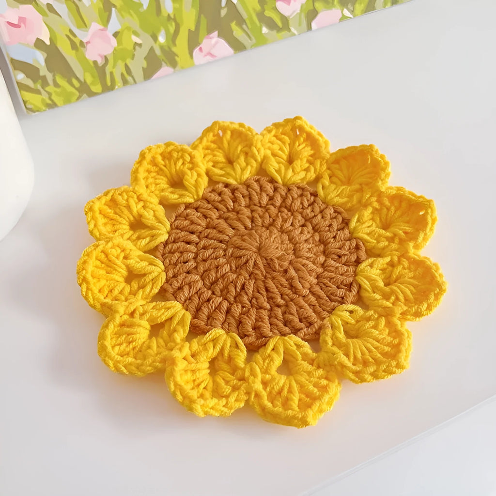 A hand-woven circular wool coaster with a floral pattern, shown as a single piece.