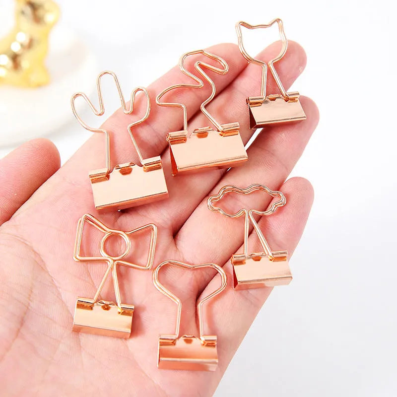 Small gold metal paper clip with a decorative bow charm attached.