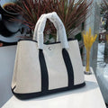Women's canvas bucket tote bag with leather trim in black colour showing open pocket and crossbody strap