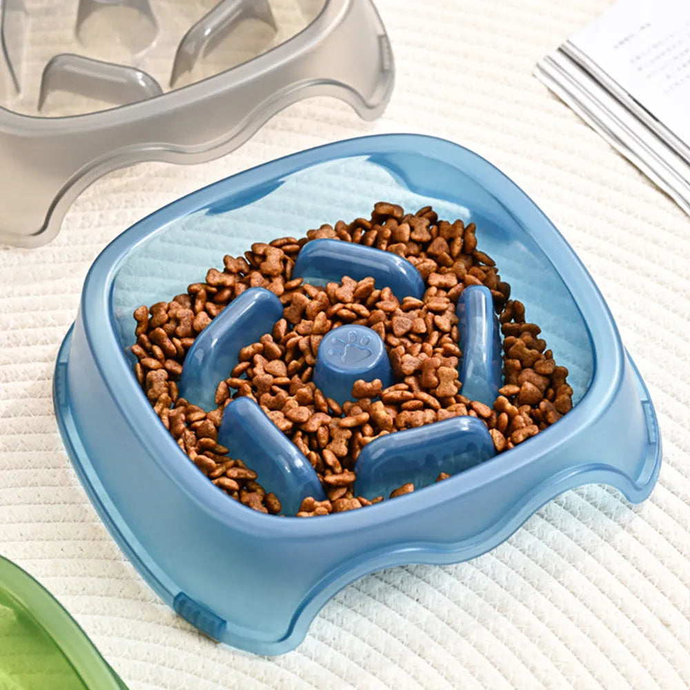 A blue plastic slow-feeder dog bowl on a wooden floor.