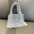 Silver cotton thread evening clutch covered in shiny rhinestones with an open outer pocket and shoulder strap.