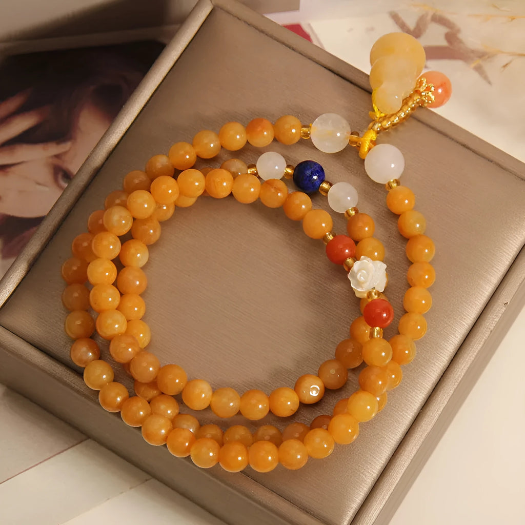 Women's multi-circle bracelet with three strands of natural Jinsi Jade beads and a resin flower calabash pendant on a white background