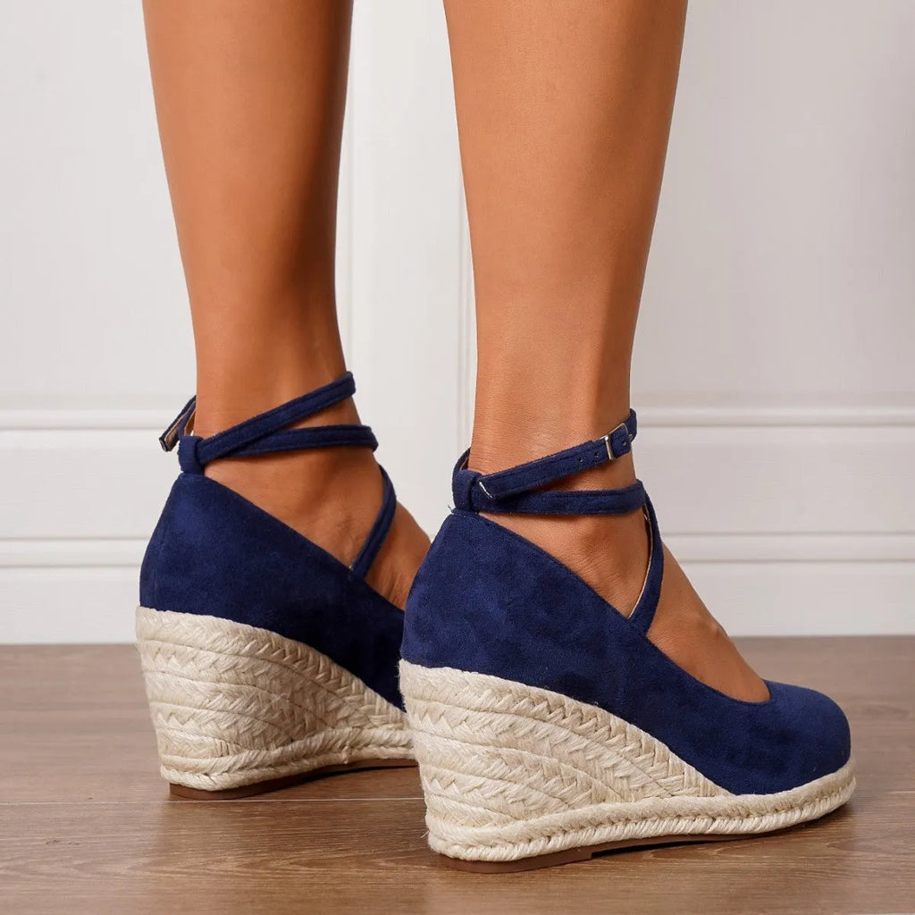 Dark blue straw woven wedge closed toe high heels with buckle fastening on a light background
