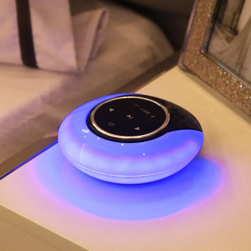 Blue Bluetooth desk lamp with speakers folded on a desk next to a charging cable.