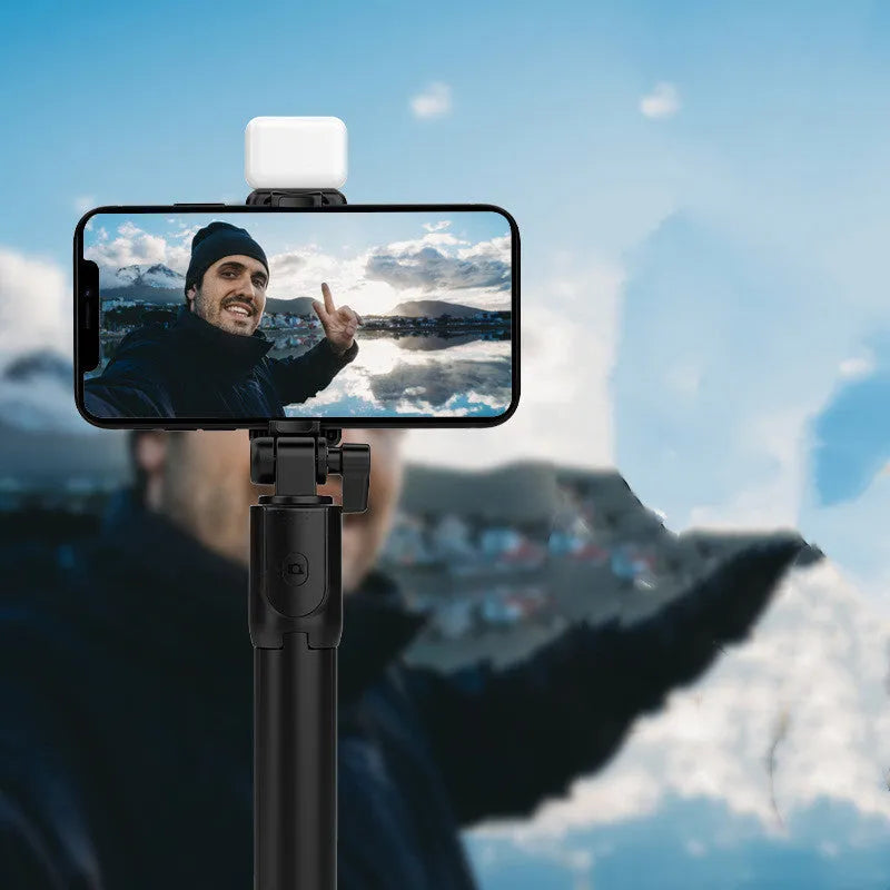 Black Bluetooth selfie stick with integrated tripod and 360-degree rotating phone holder, shown with a remote control.