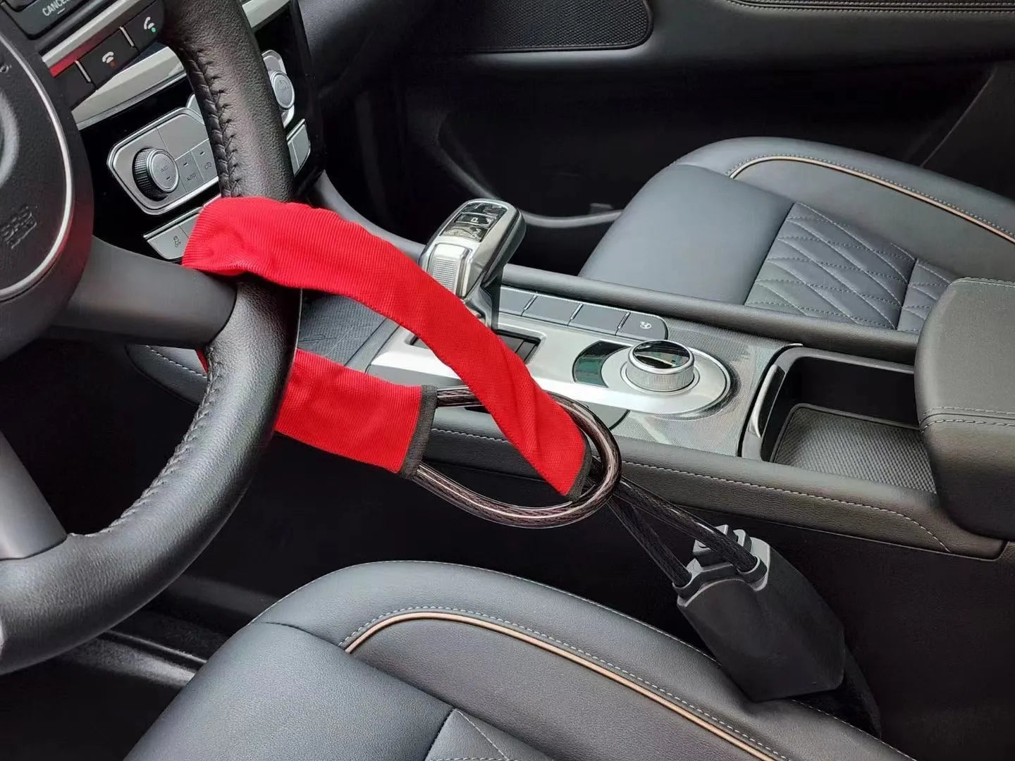 A red iron steering wheel lock with a copper core for General Motors cars, shown with its wire rope extended.